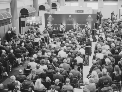 Black and white image on conference panel debate with large audience seated