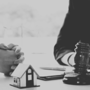 Black and white image of auction hammer and house.