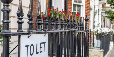 Railings outside proeprty with flowers and 'To let' signage in black text.