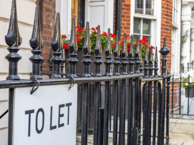 Railings outside proeprty with flowers and 'To let' signage in black text.