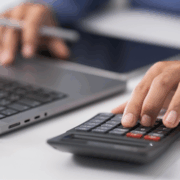 A man's hands typing and hand on a calculator