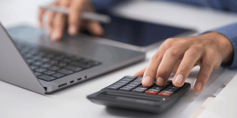 A man's hands typing and hand on a calculator