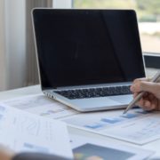 Laptop open with person speaking and graphs