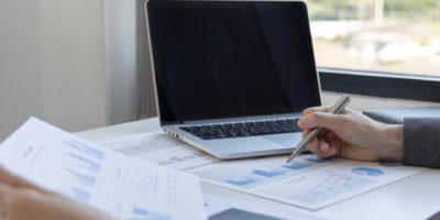 Laptop open with person speaking and graphs