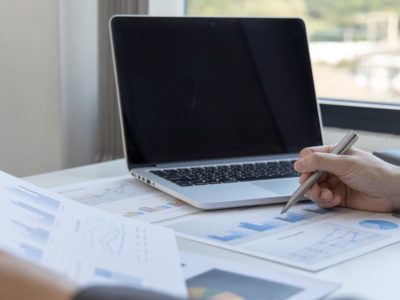 Laptop open with person speaking and graphs